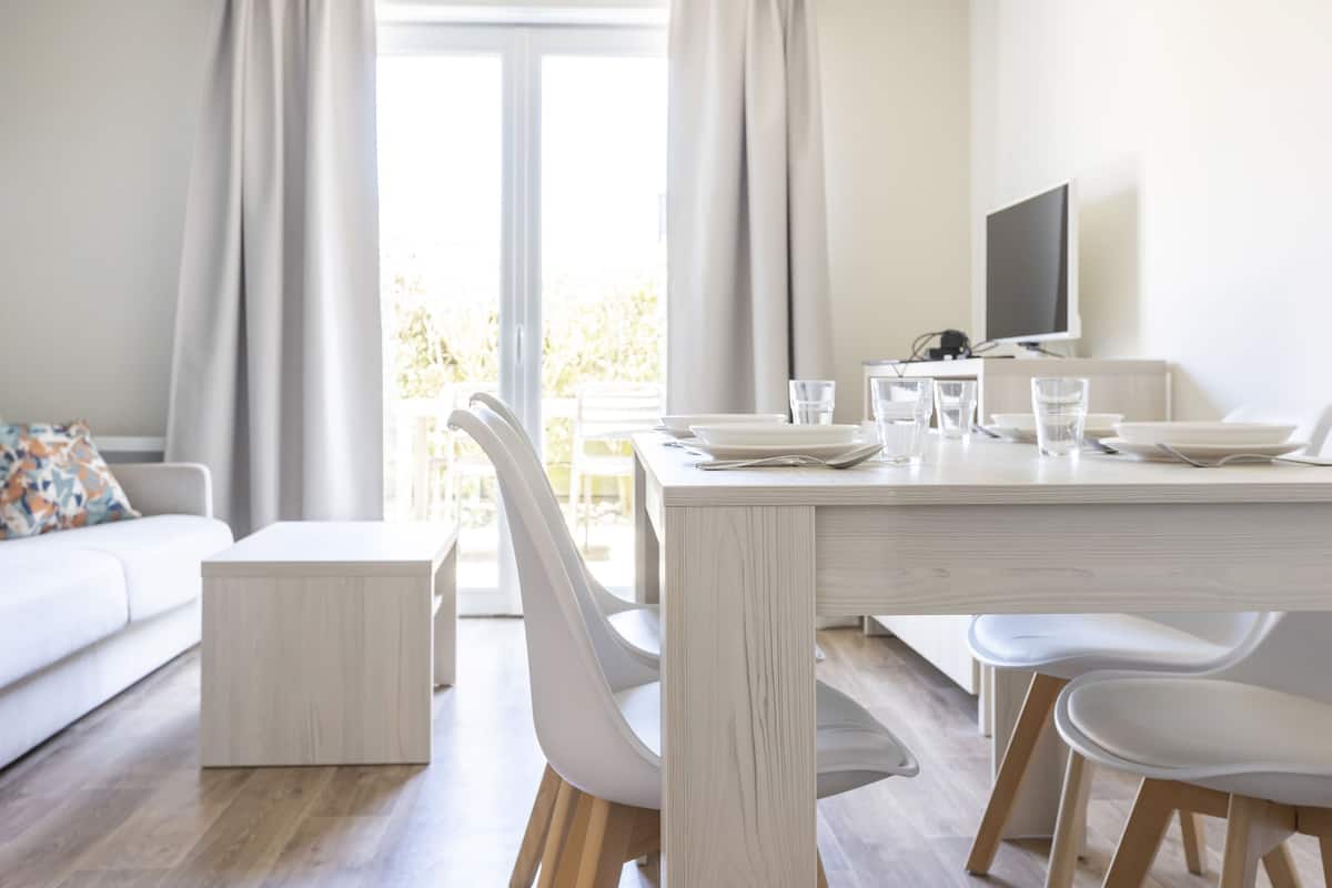 Un espace repas moderne avec une table blanche, des chaises et un téléviseur.