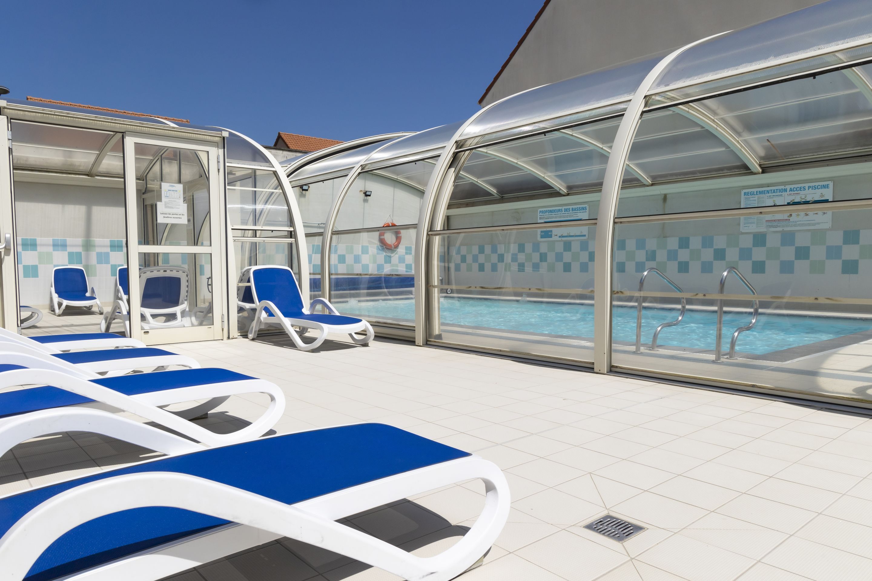 Un espace aménagé au bord de la piscine, avec des chaises longues et une zone de baignade couverte.