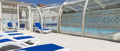 A poolside area with lounge chairs and a covered swimming area.