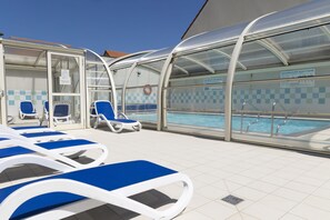 Un espace aménagé au bord de la piscine, avec des chaises longues et une zone de baignade couverte.