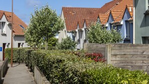 A row of residential buildings with red-tiled roofs and white walls, a wooden fence, and a clear sky. - Residence Les Villas De La Baie (Le Crotoy)