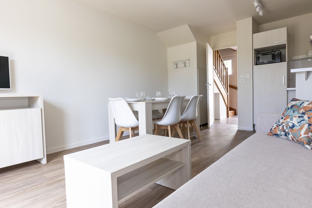 Una sala de estar moderna con un sofá, una mesa de centro y un comedor con sillas y una mesa.