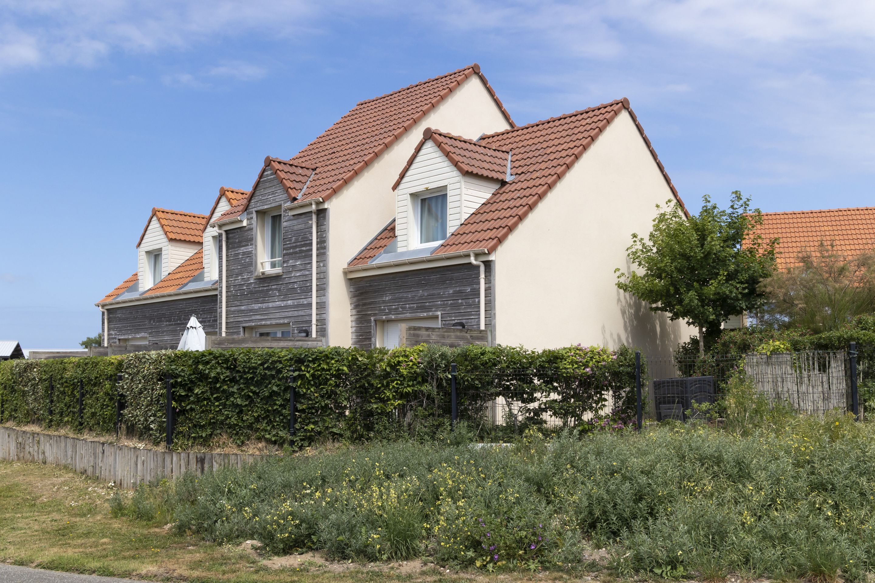 A row of two-story houses with red-tiled roofs and white walls.