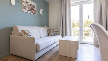 Un salon moderne avec un canapé, une table basse et une vue sur l’extérieur grâce à une porte-fenêtre coulissante.