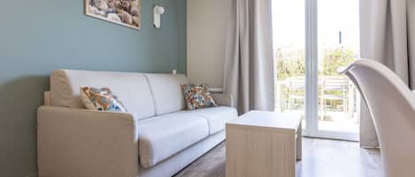 Ein modernes Wohnzimmer mit einer Couch, einem Couchtisch und Blick ins Freie durch eine Schiebetür.
