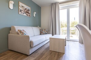 Una sala moderna con sofá, una mesa de centro y vistas al exterior a través de un ventanal corredero.