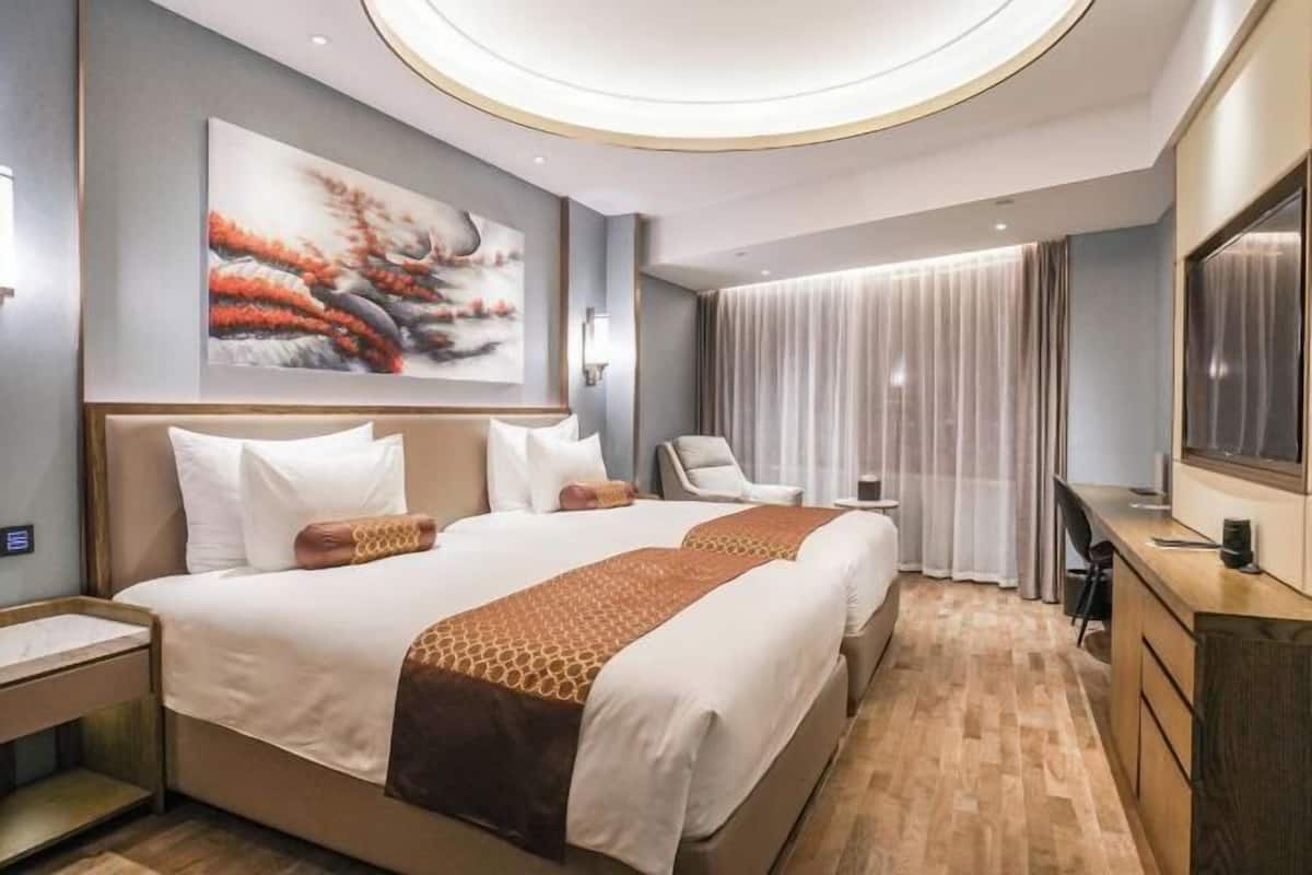 Une chambre d’hôtel moderne, dotée d’un grand lit, d’un bureau et d’une télévision.