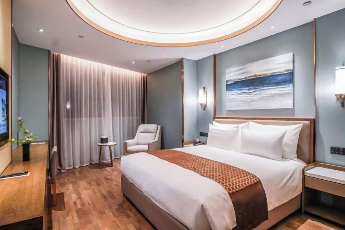 Une chambre d’hôtel moderne dotée d’un grand lit, d’une télévision, d’un bureau et offrant une vue sur l’océan.