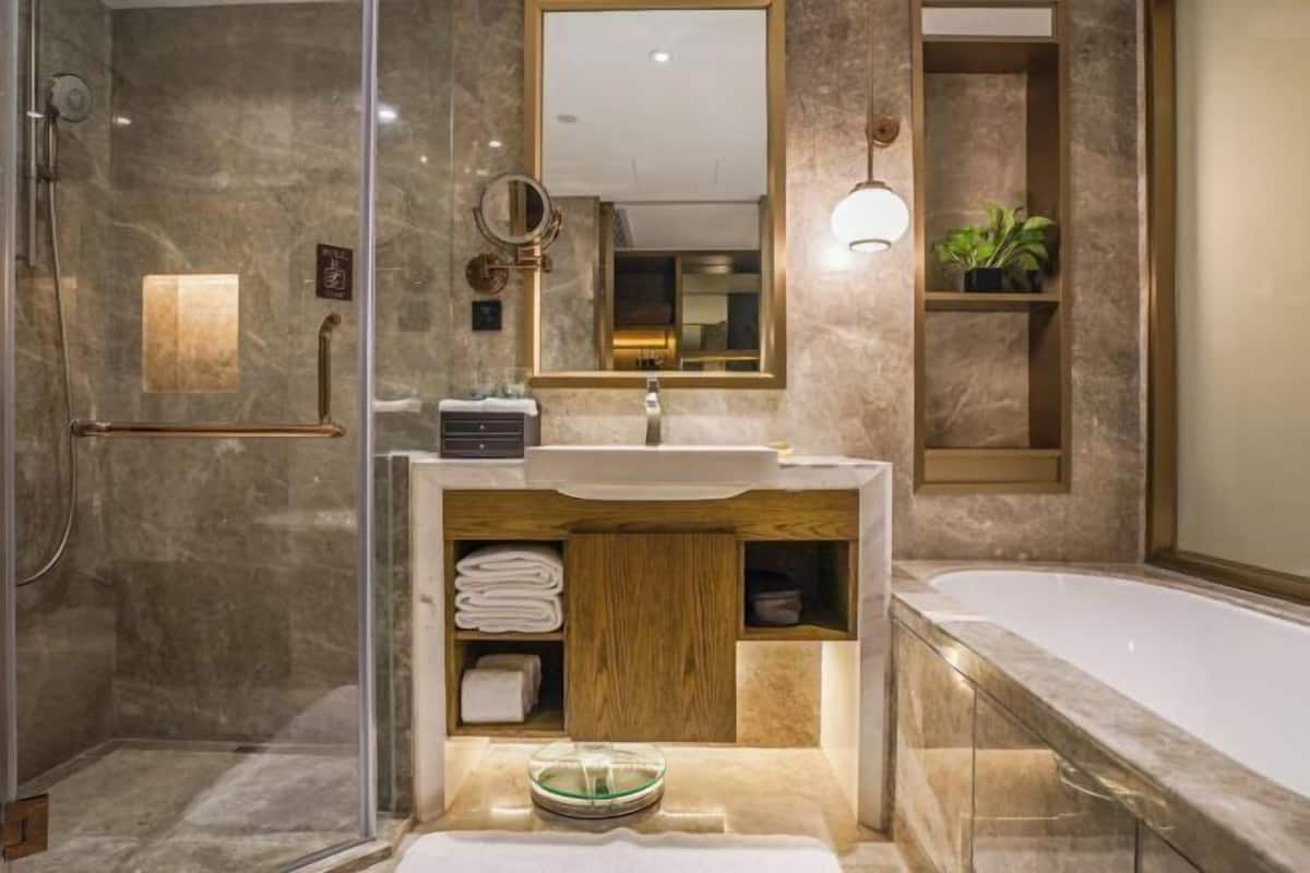 Une salle de bain moderne avec une douche à parois de verre, un meuble-lavabo en bois et une grande baignoire.
