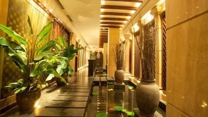 A corridor with potted plants, a reflective floor, and a patterned ceiling. - Shaoxing Xianheng Grand Hotel (Lu Xun's hometown Yintai store) (Shaoxing)