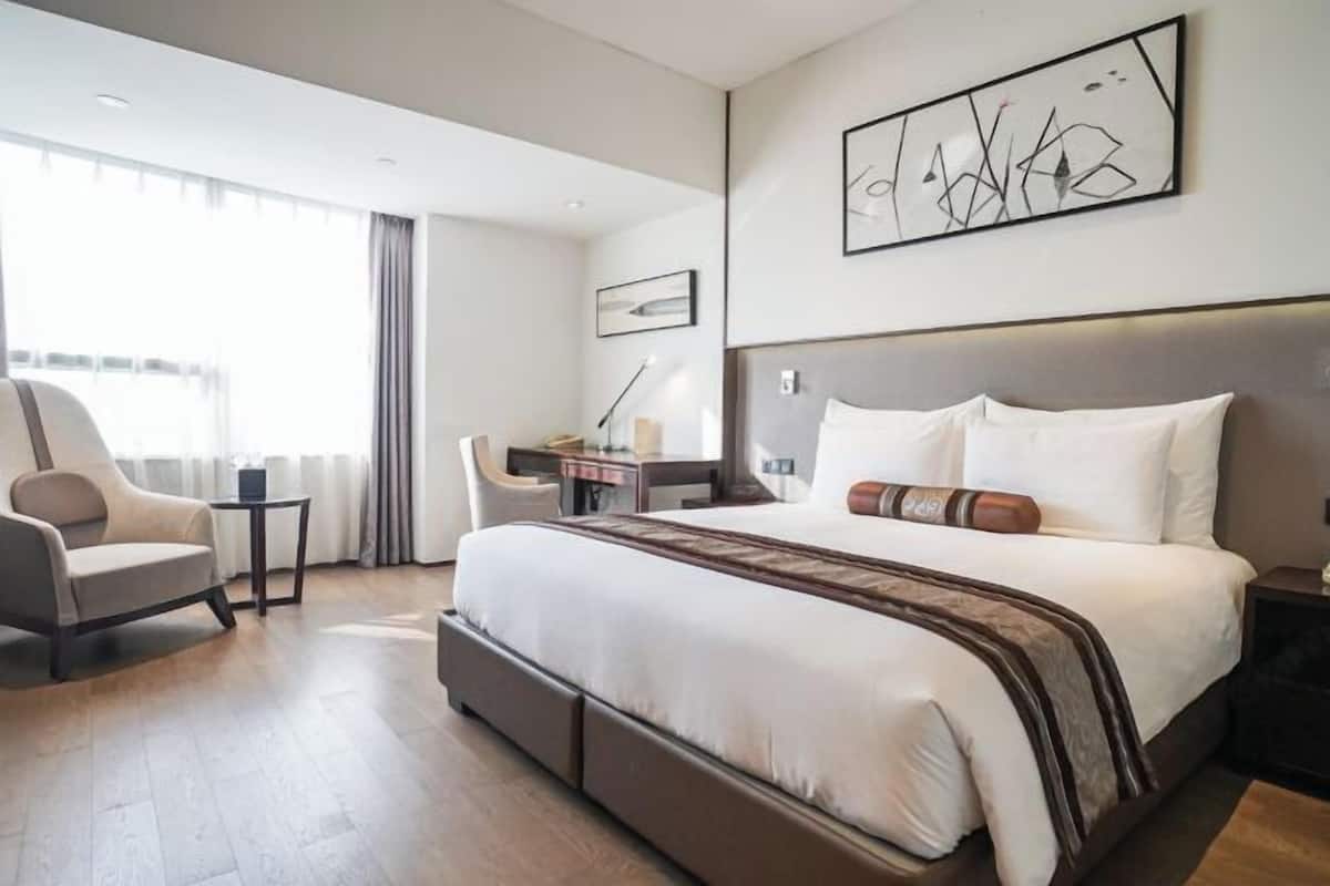 Une chambre d’hôtel moderne avec un grand lit, un bureau, une chaise et une grande fenêtre.