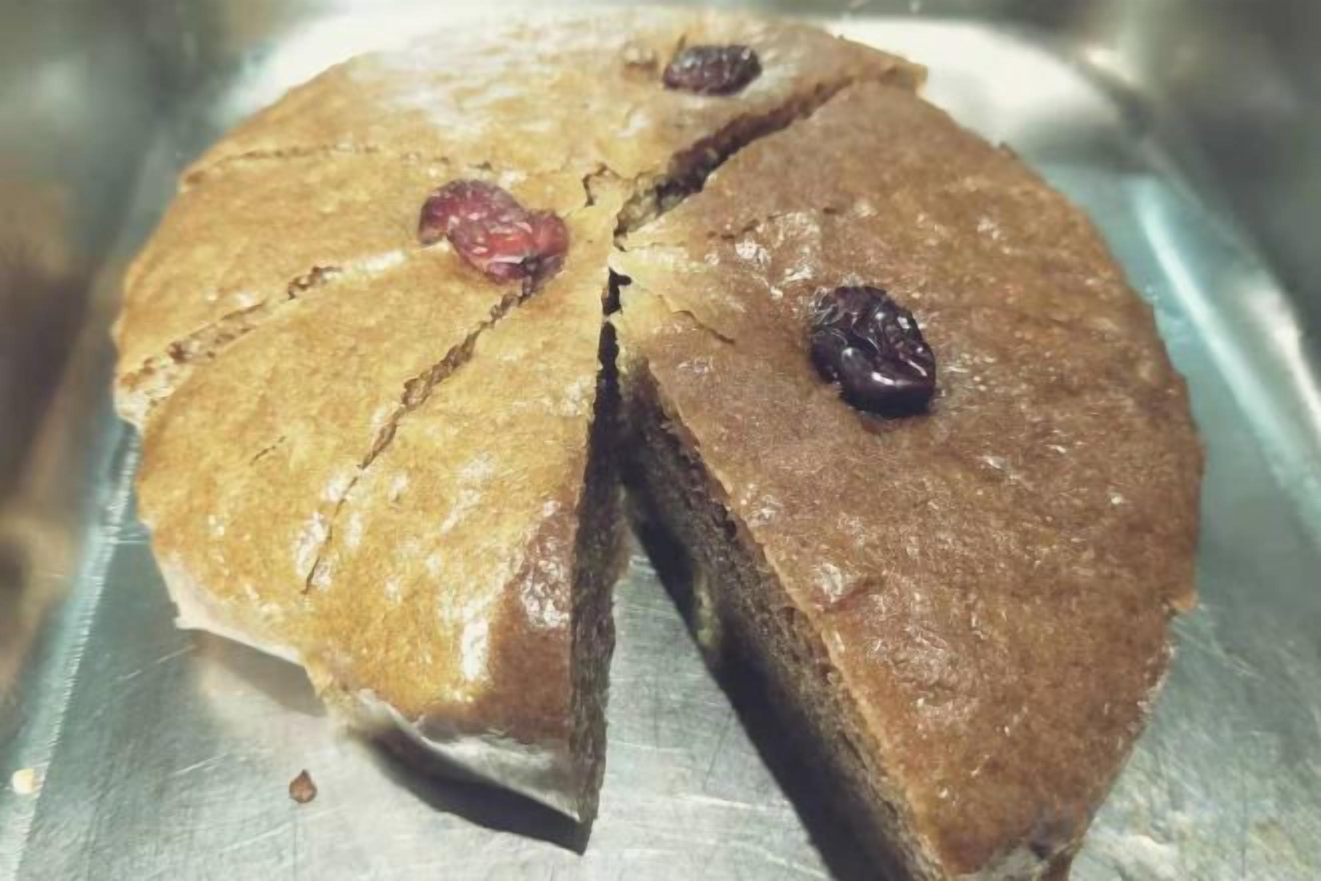 Egy kerek torta, amiből egy szeletet kivágtak, és egy fémfelületre helyezték.