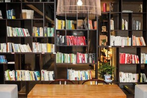 Une pièce avec une table et des chaises en bois, entourée d’étagères remplies de livres.