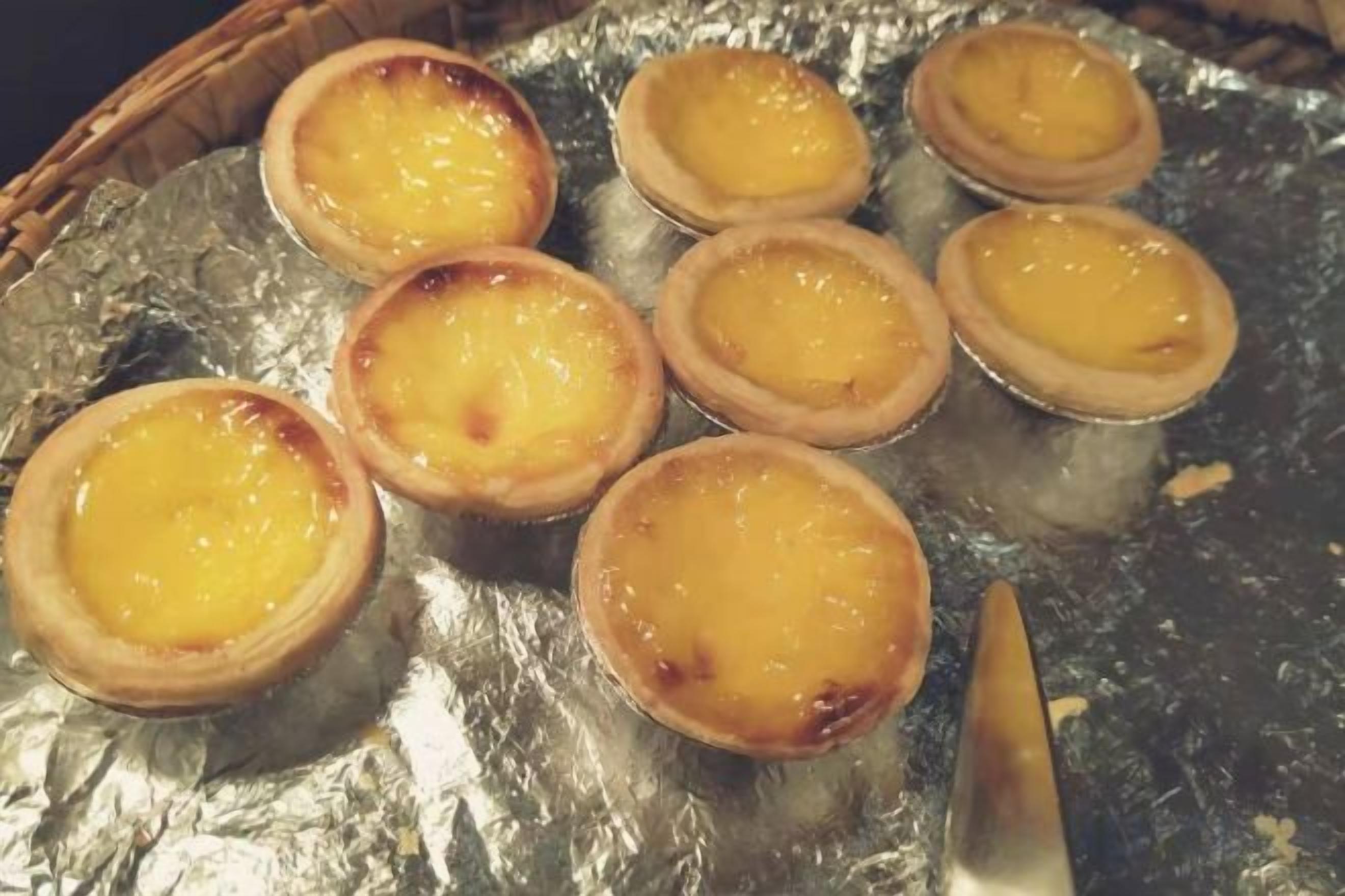 A tray of custard tarts on foil.