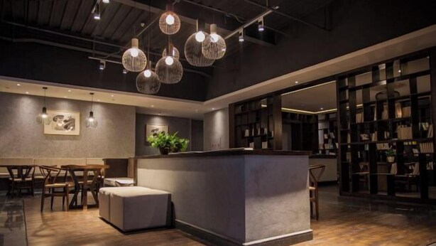 Ein modernes Interieur mit einer zentralen Bar, Holzböden und hängenden Pendelleuchten.