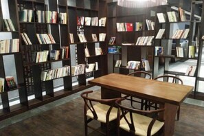 Une bibliothèque avec des étagères, une table en bois et des chaises.