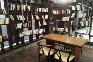 Una biblioteca con estanterías, una mesa de madera y sillas.