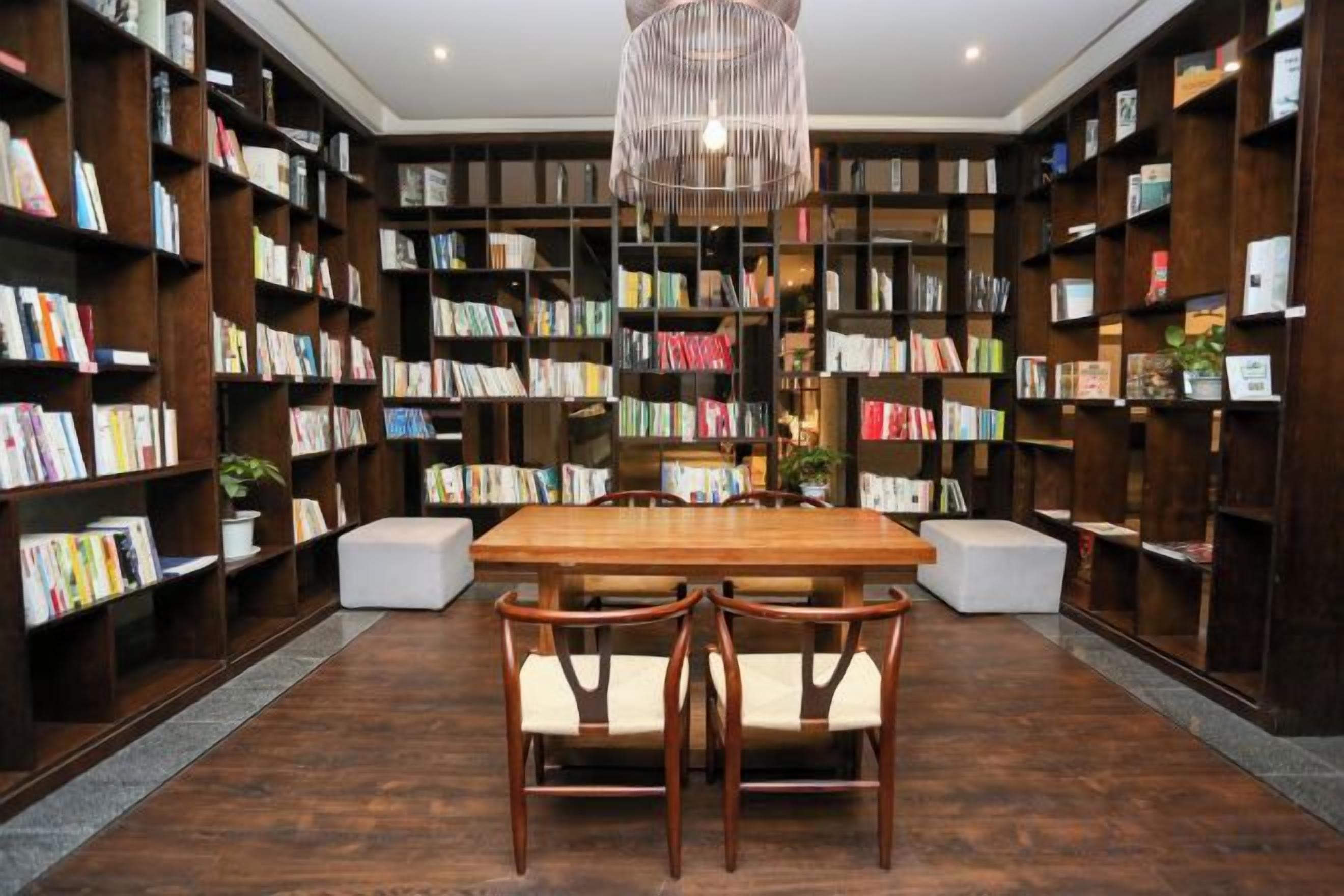 Una biblioteca con estanterías, una mesa de madera y sillas.