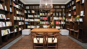 Una biblioteca con estanterías, una mesa de madera y sillas.