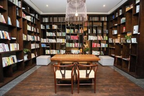 Una biblioteca con estanterías, una mesa de madera y sillas.