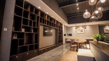 A modern interior with a long reception desk, a seating area, and a wall-mounted TV.