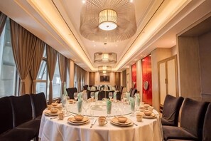 Un comedor con mesas redondas, sillas y una araña.