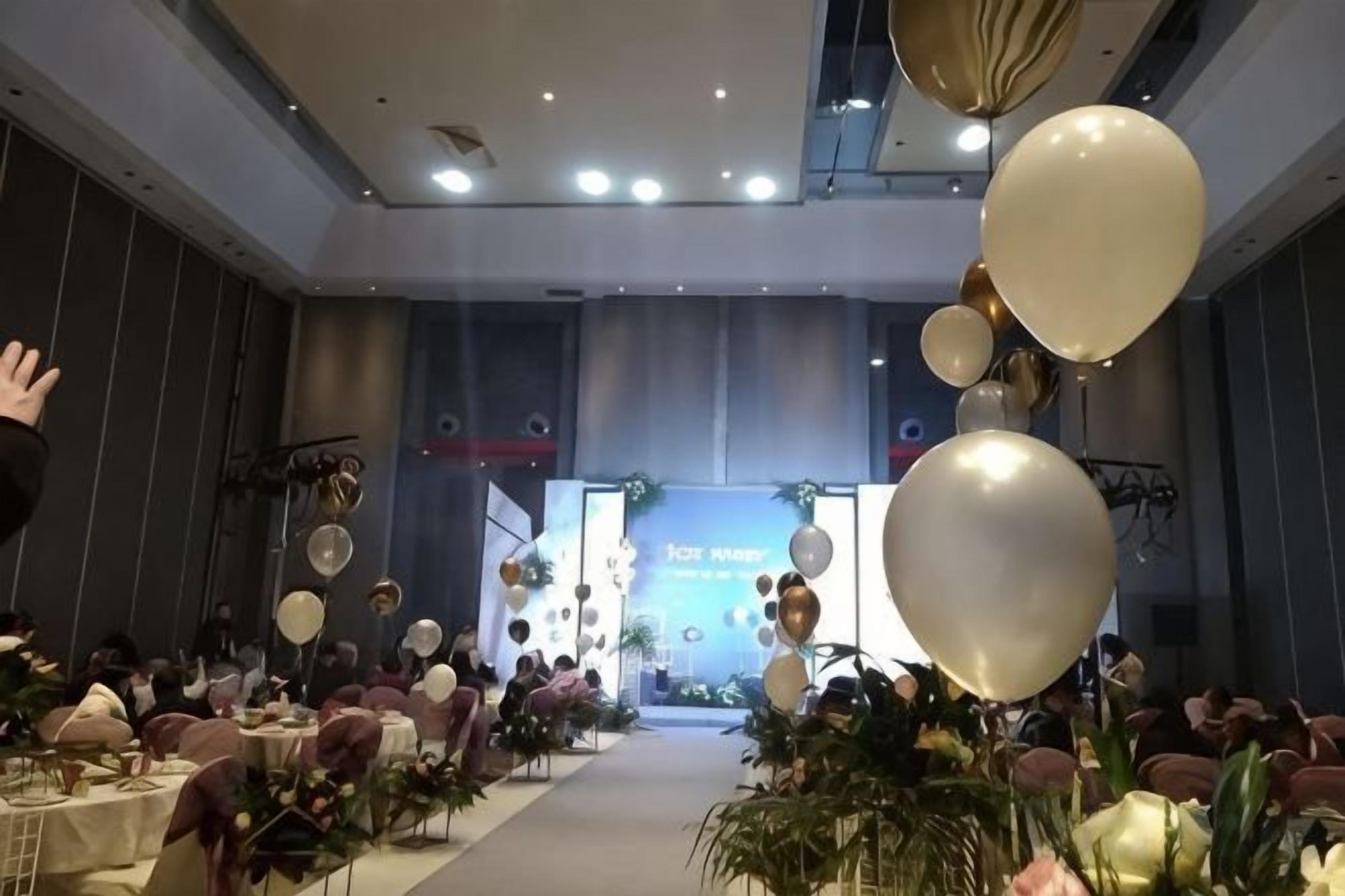 Un salón de banquetes con mesas redondas, sillas y globos.