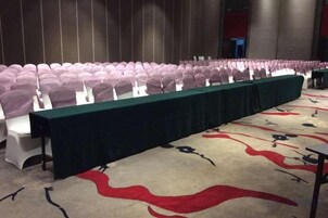 Un salón de conferencias con filas de sillas y una mesa larga, ideal para reuniones o eventos.