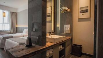 Una habitación de hotel moderna con un espejo grande, un tocador de madera, una cama y una ventana con cortinas.