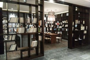 Una biblioteca con estanterías, una mesa de lectura y sillas.