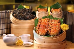A table with bamboo steamers containing seafood, a teapot, and a cup. - Laixian Island Hotel (Taizhou)