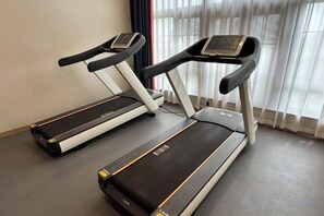 Dos cintas de correr en una habitación con ventana y cortinas.