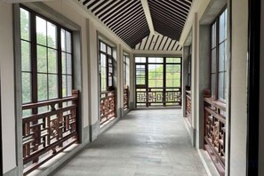 A corridor with wooden railings and large windows.