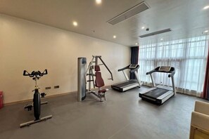 Un gimnasio con cintas de correr, una máquina de pesas y un banco.