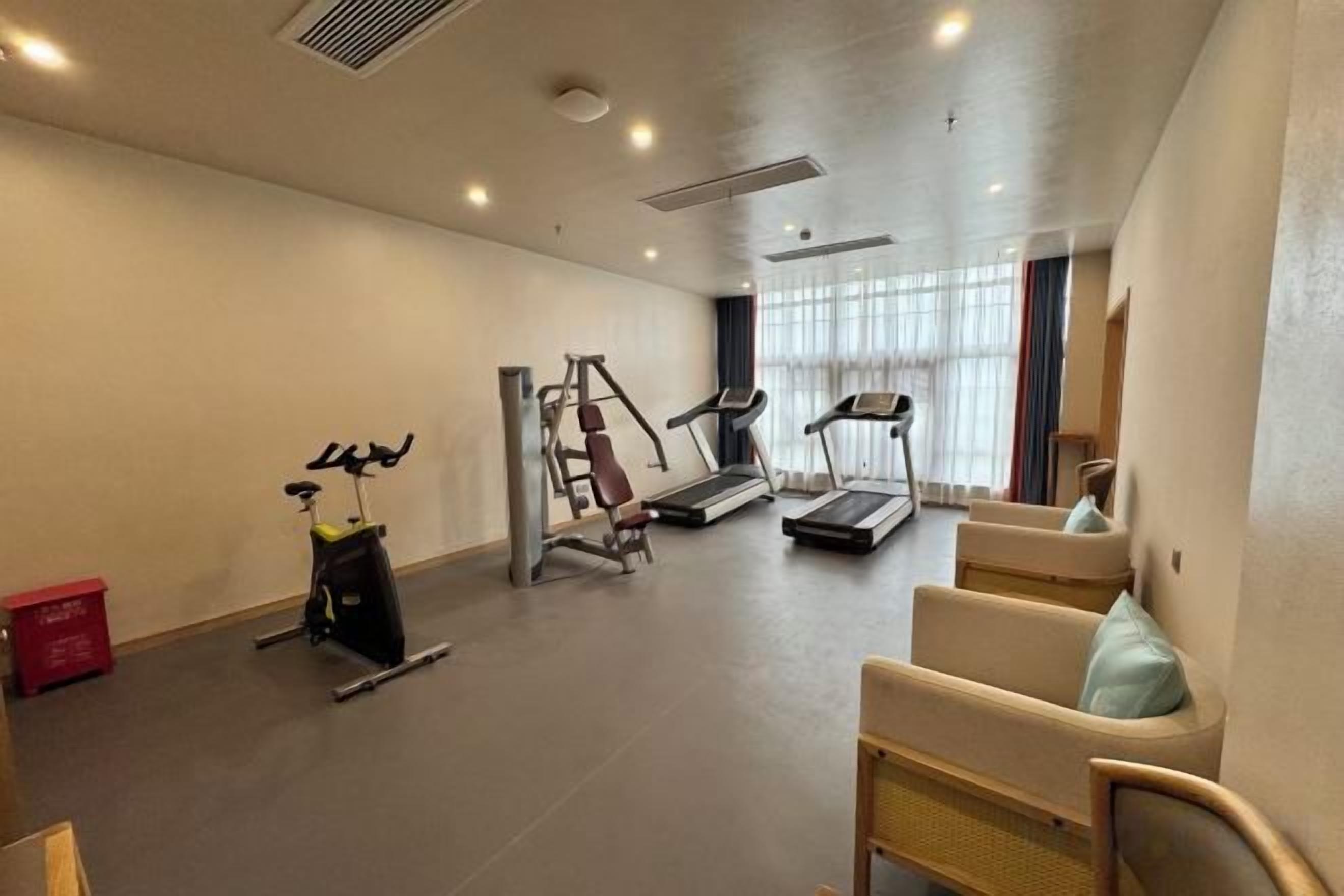 Un gimnasio con equipo de ejercicio, una cinta de correr y una banca.