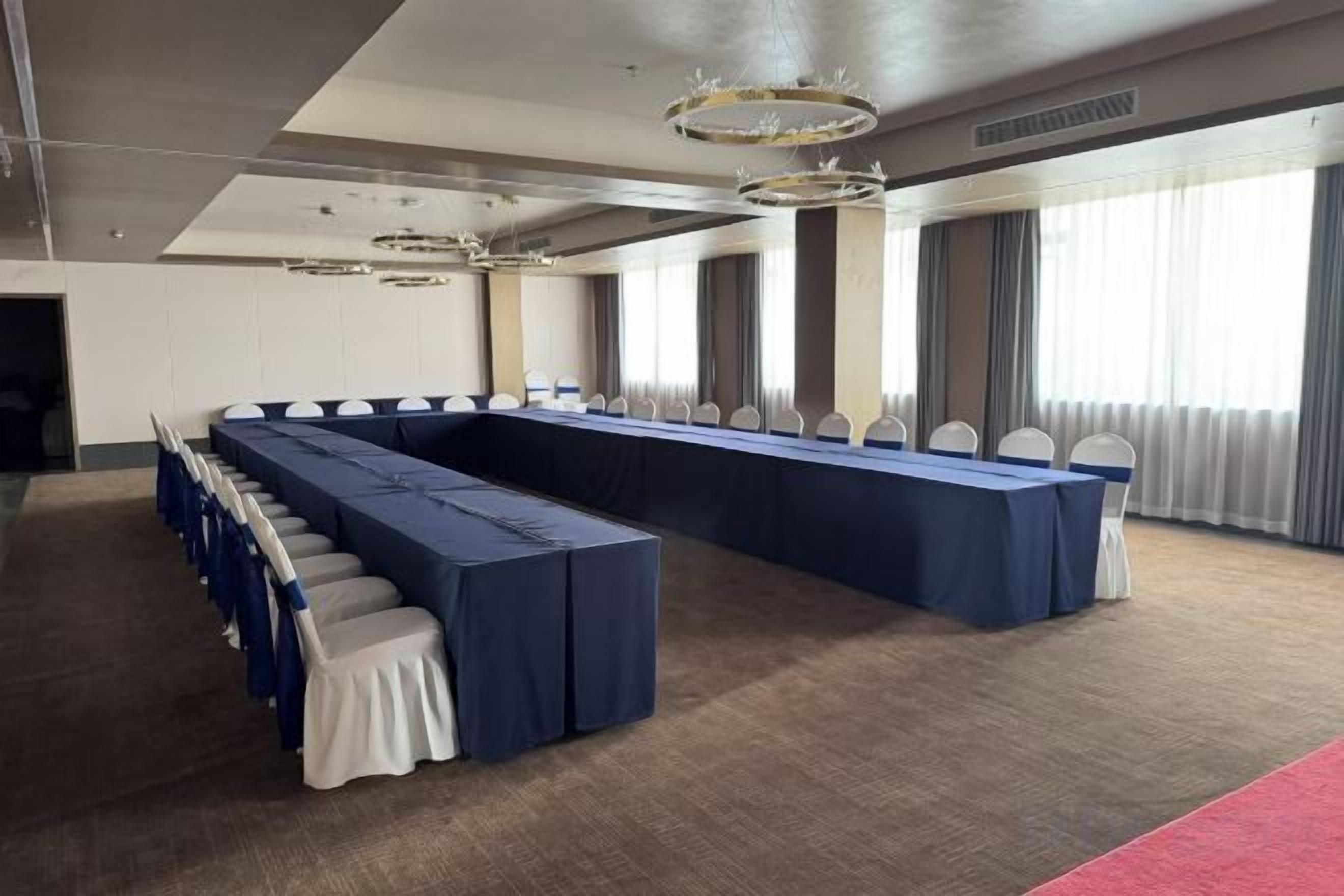 Un salón de conferencias con una larga mesa, sillas y piso alfombrado.