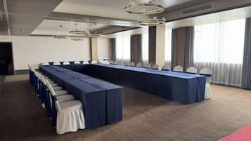 Un salón de conferencias con una larga mesa, sillas y piso alfombrado.