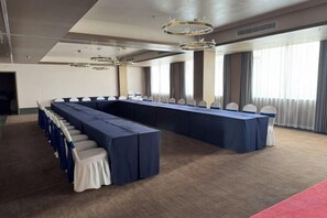 Un salón de conferencias con una larga mesa, sillas y piso alfombrado.