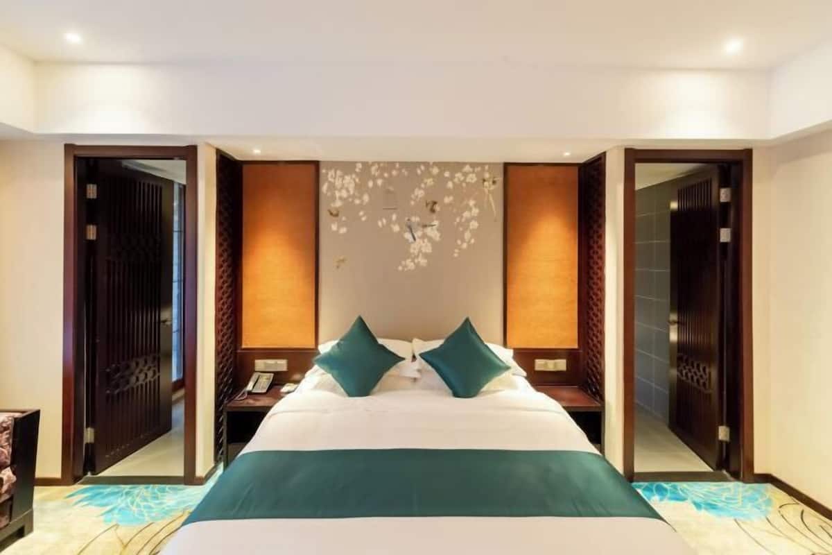 Una camera d'hotel con un letto grande, due comodini, uno specchio e un elemento decorativo a parete.