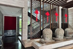 Un interior moderno con una pared de acento roja, una escalera con detalles decorativos y esculturas de piedra.