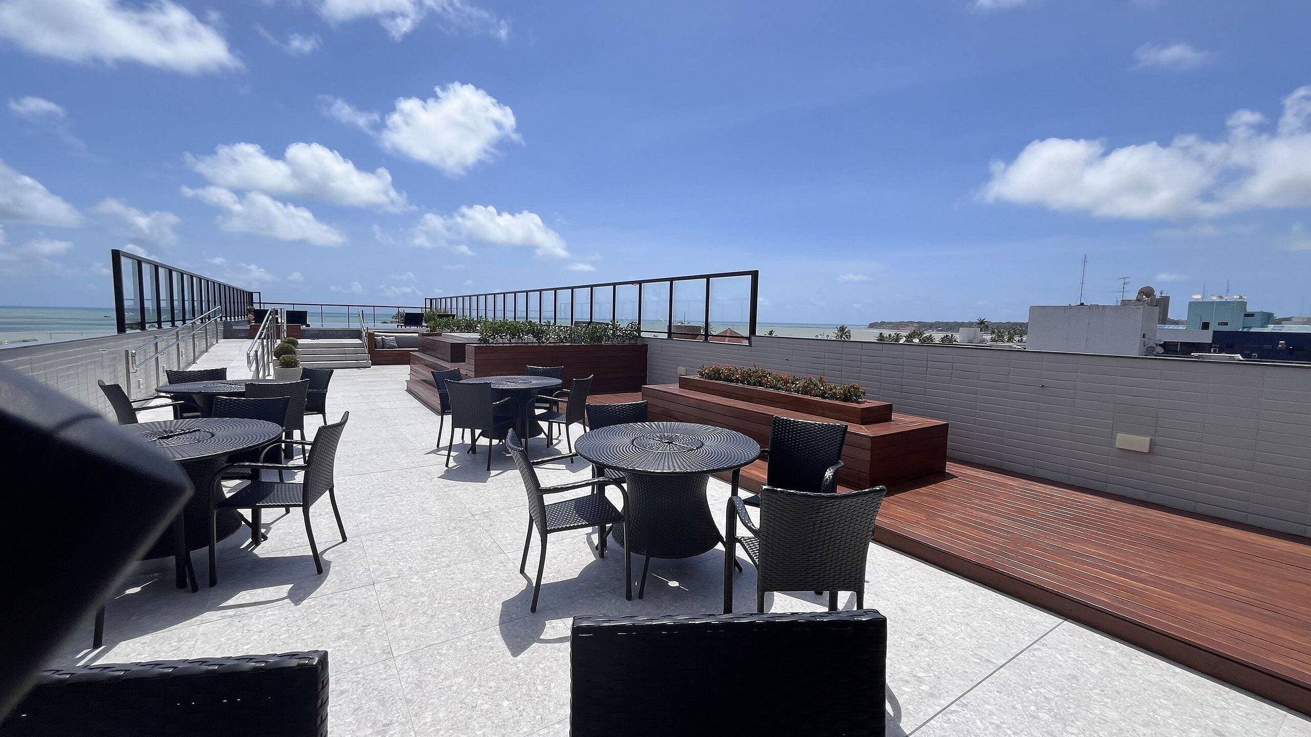 Una terrazza sul tetto con posti a sedere all'aperto, vista sull'oceano e ringhiera che si affaccia sulla città.