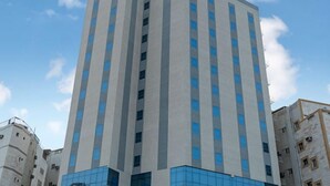 Ένα πολυώροφο κτίριο με μοντέρνο σχεδιασμό, που διαθέτει μια ενδιαφέρουσα μίξη από γυάλινες και τσιμεντένιες προσόψεις.