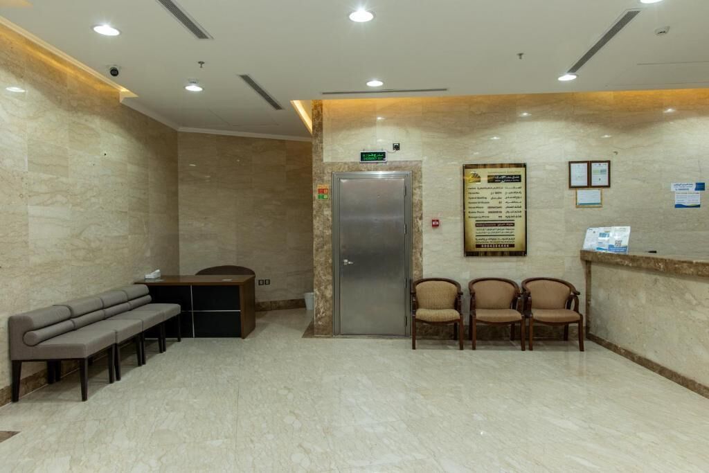 A reception area with a marble floor, a reception desk, a bench, and three chairs.
