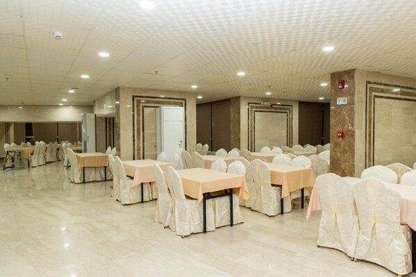 A large banquet hall with multiple tables and chairs, arranged in rows.