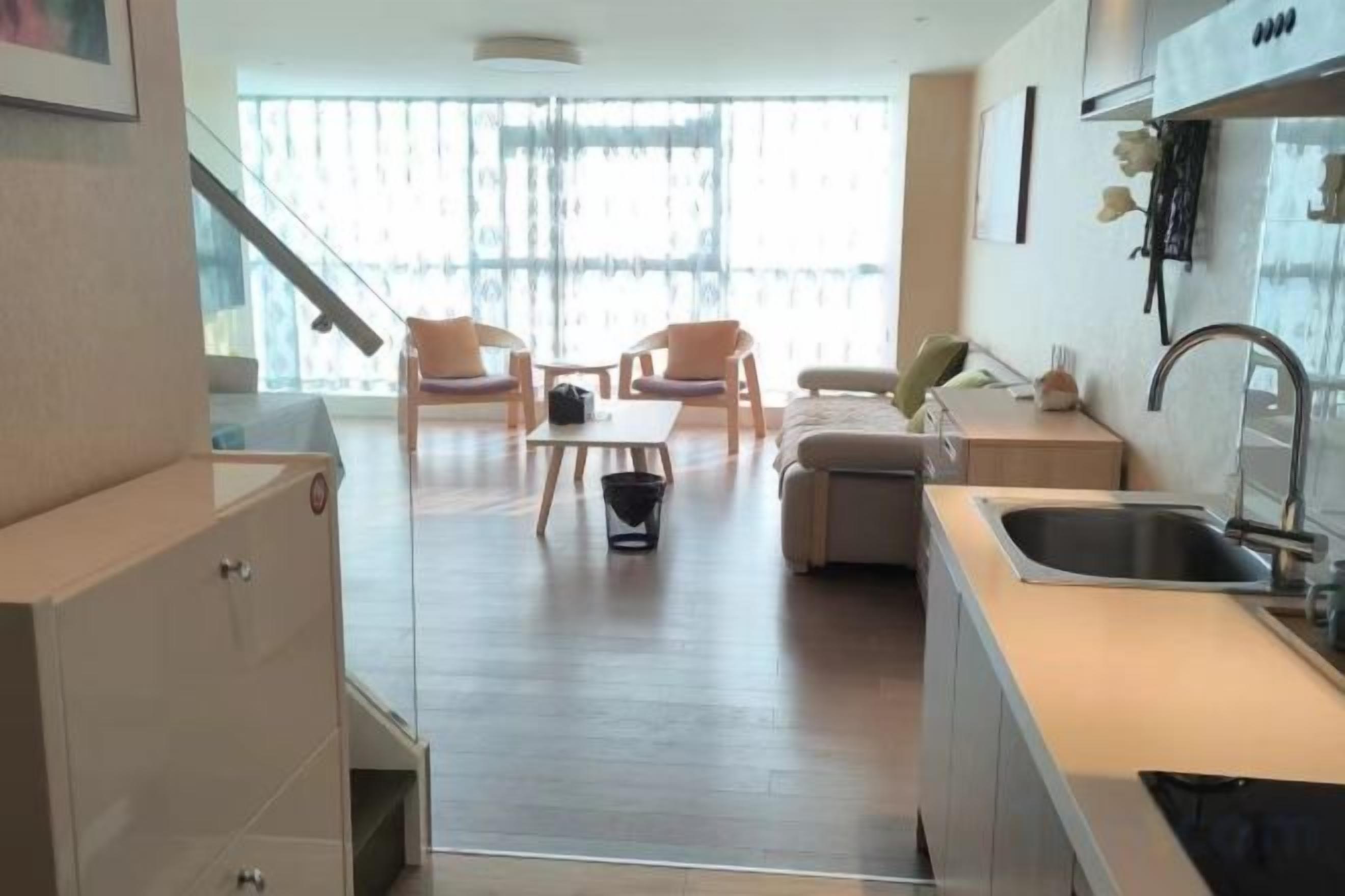 A modern kitchen with a sink, a dining area with chairs, and a view through large windows.