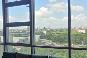 A room with a large window offering a view of a cityscape and greenery.