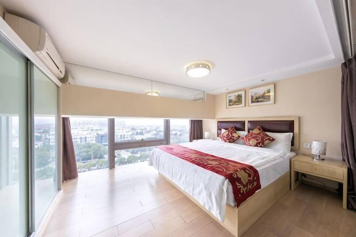 Een slaapkamer met een groot bed, een nachtkastje en uitzicht op de stad.