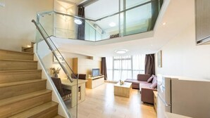 Un apartamento moderno con una escalera de madera, barandilla de vidrio, comedor, sala de estar y cocina.