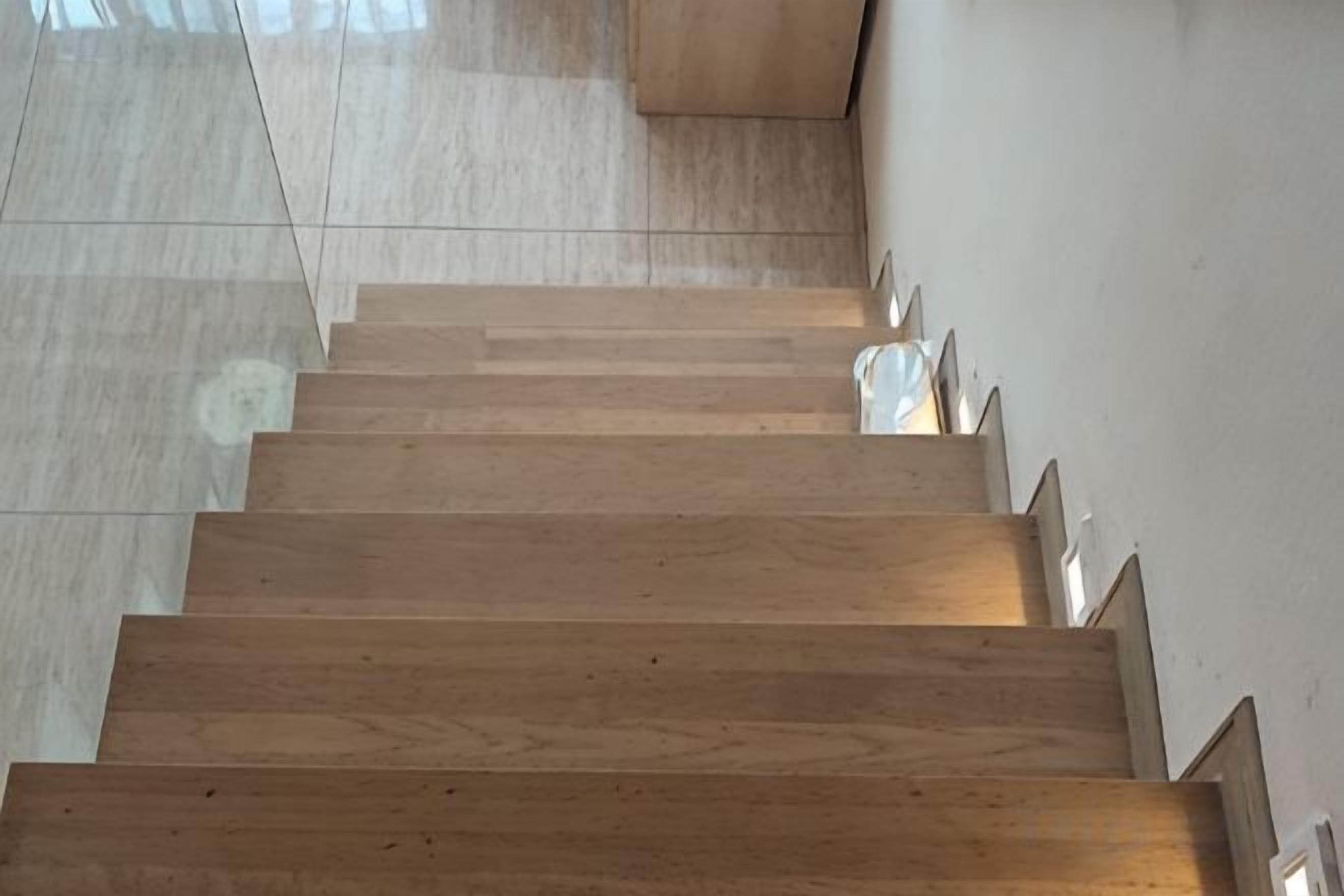 A wooden staircase with a handrail on the right side.