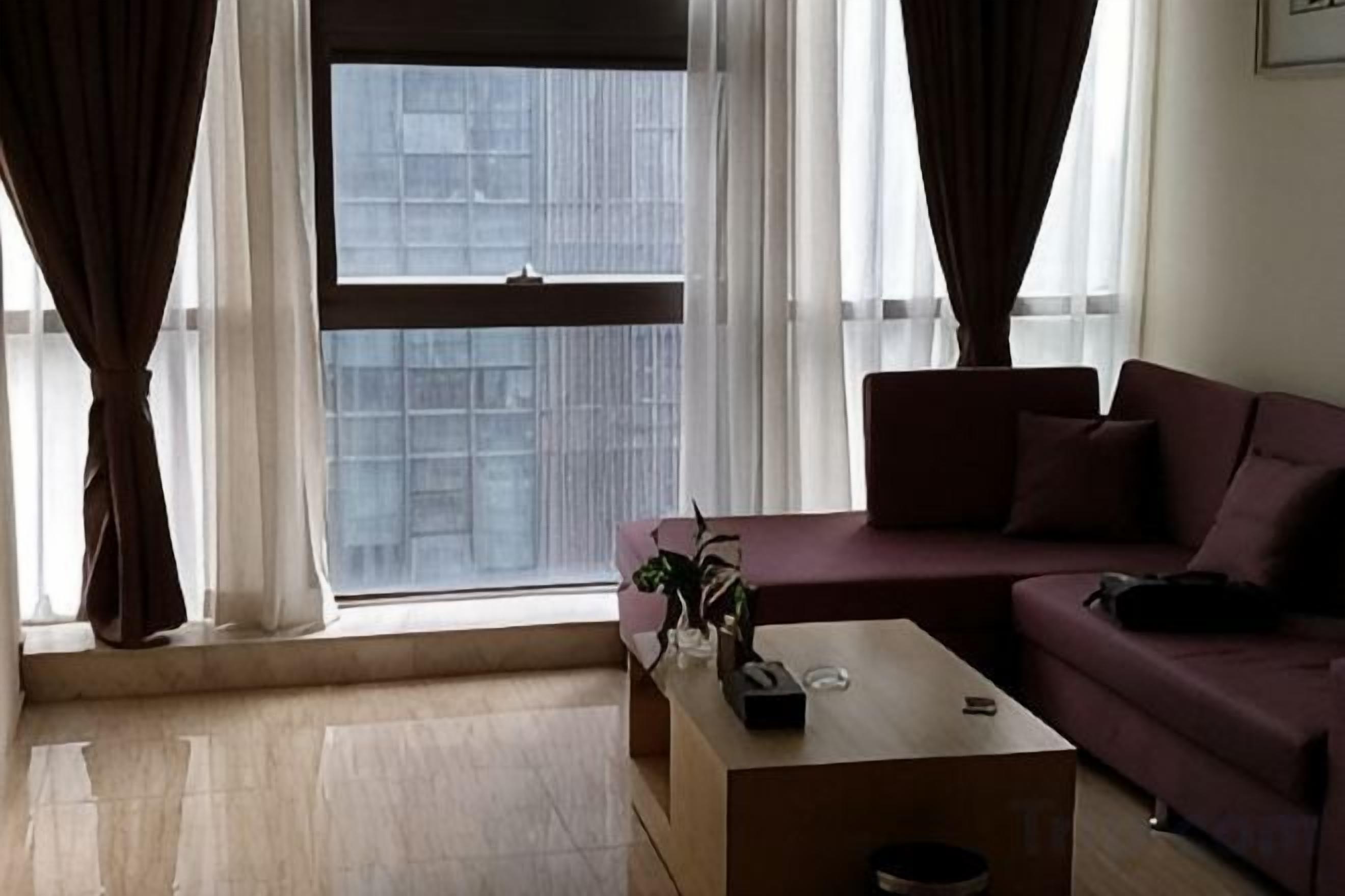 Uma sala de estar com sofá, mesa de centro e janela com cortinas.